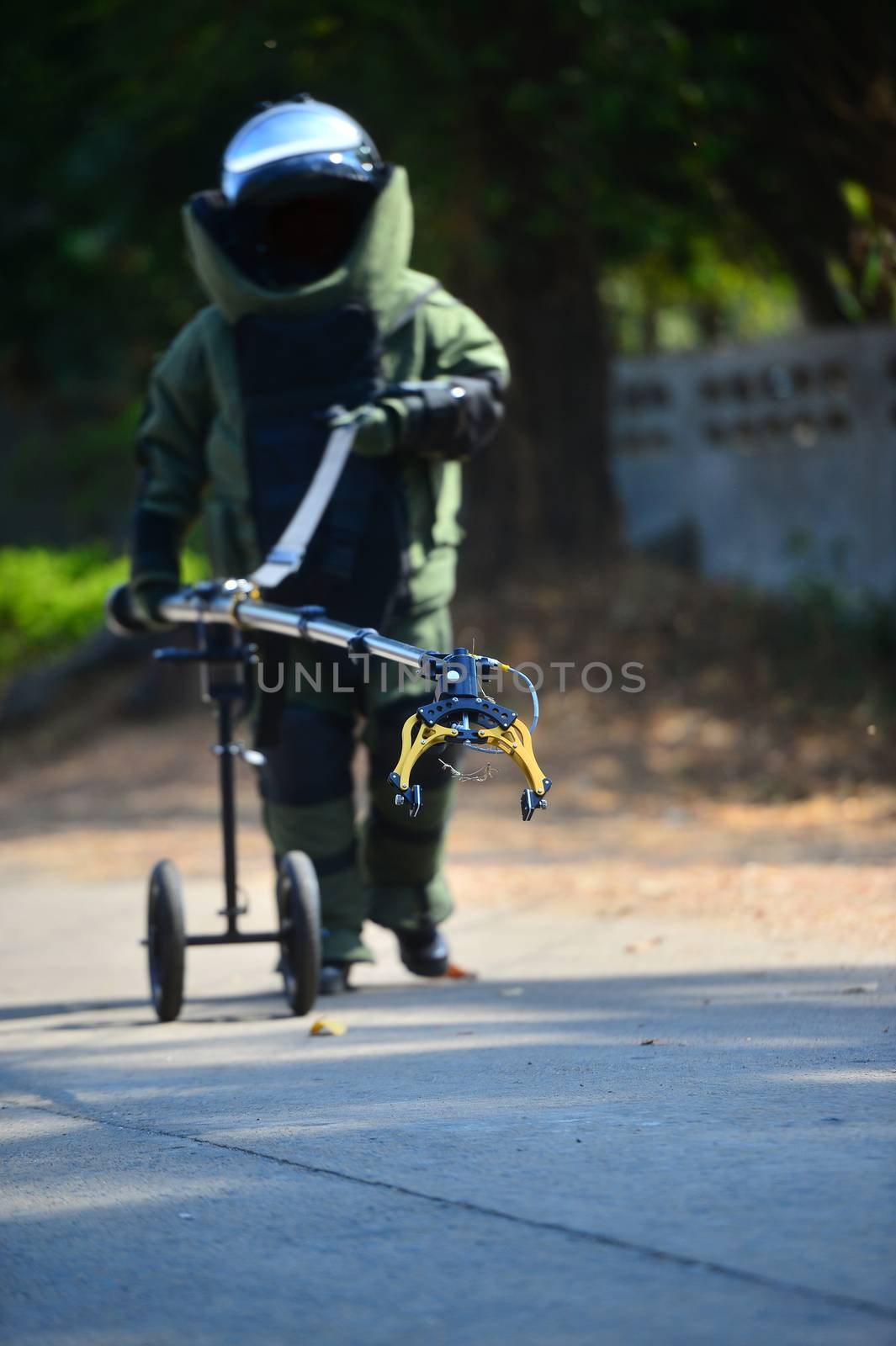 Explosive Ordnance Disposal's officer walking on the road to security check with remote robot hand