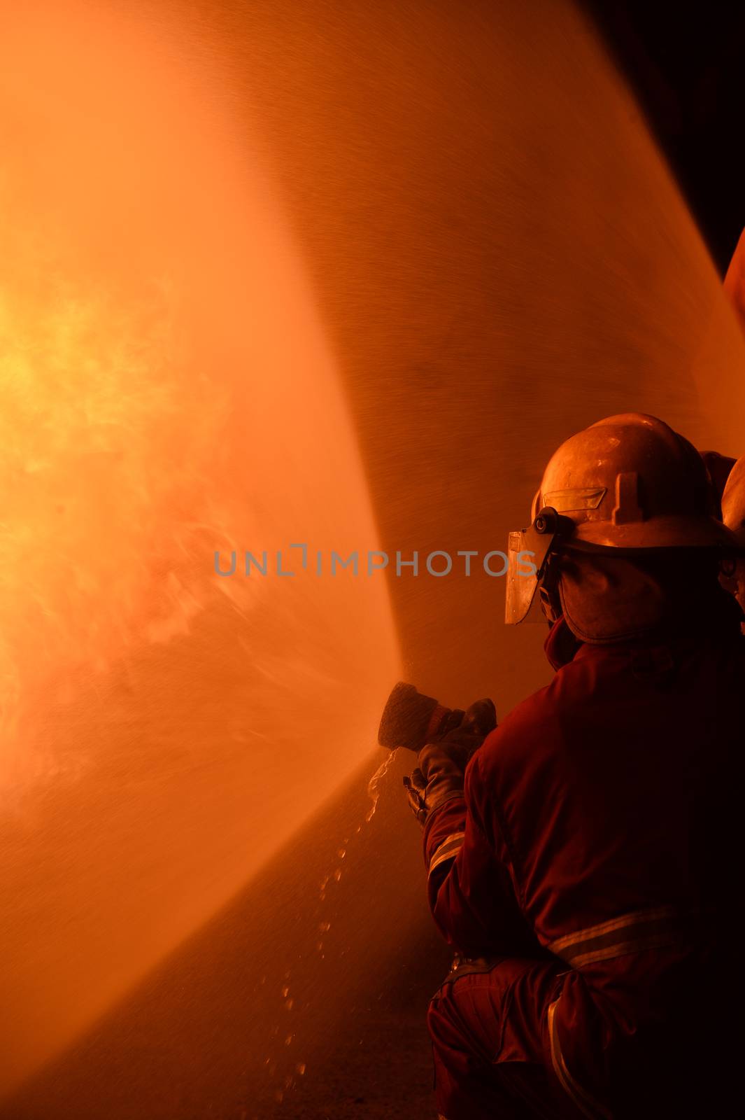 firefighters with fire hose fight with fire at night