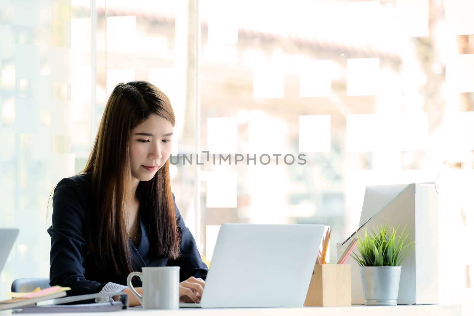 Beautiful young Asian girl working at modern office with a laptop computer for business financial analysis.