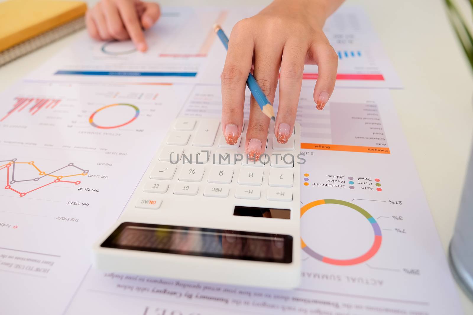 Close up of businessman or accountant hand holding pencil working on calculator to calculate financial data report,  by nateemee