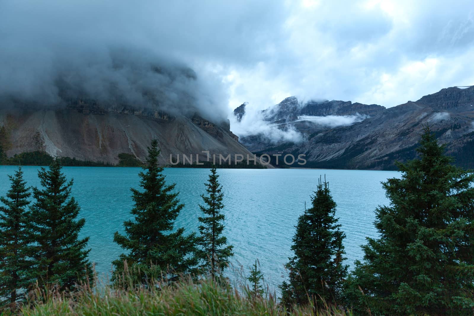 Bow lake with its turquoise water and mountains on the background covered with morning fog, Alberta, Canada