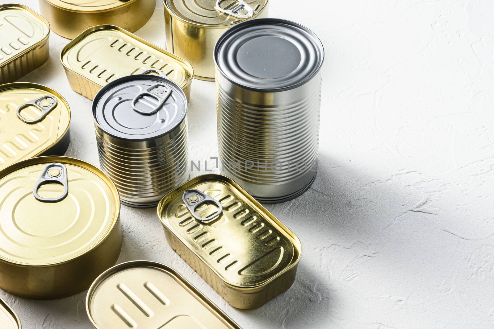 Various closed canned food, fish , fruits, vegetables, meat, soup different types of shapes top view onwhite textured background close up side view space for text