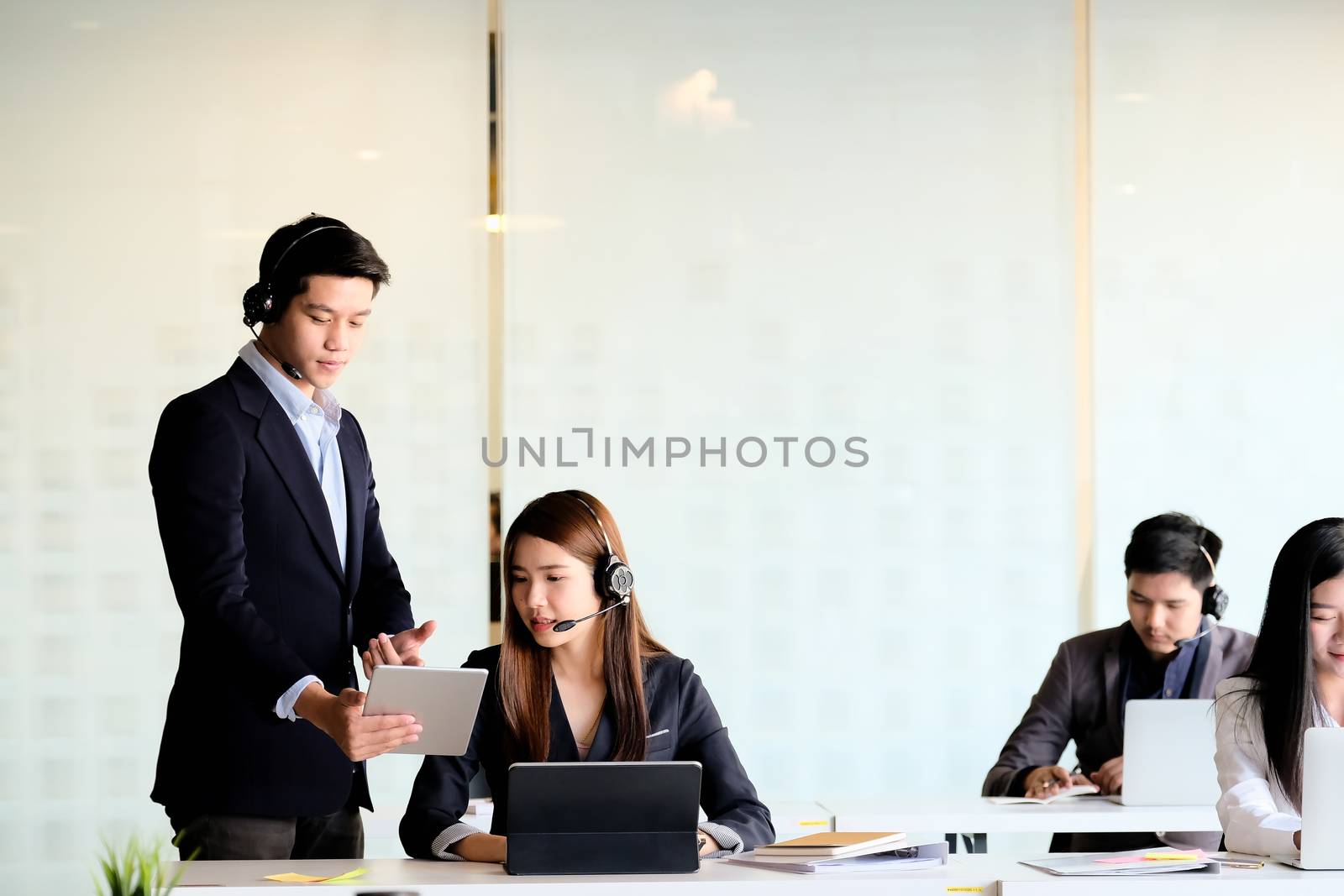 Businessman supervisor training work to businsswoman in call center office by nateemee