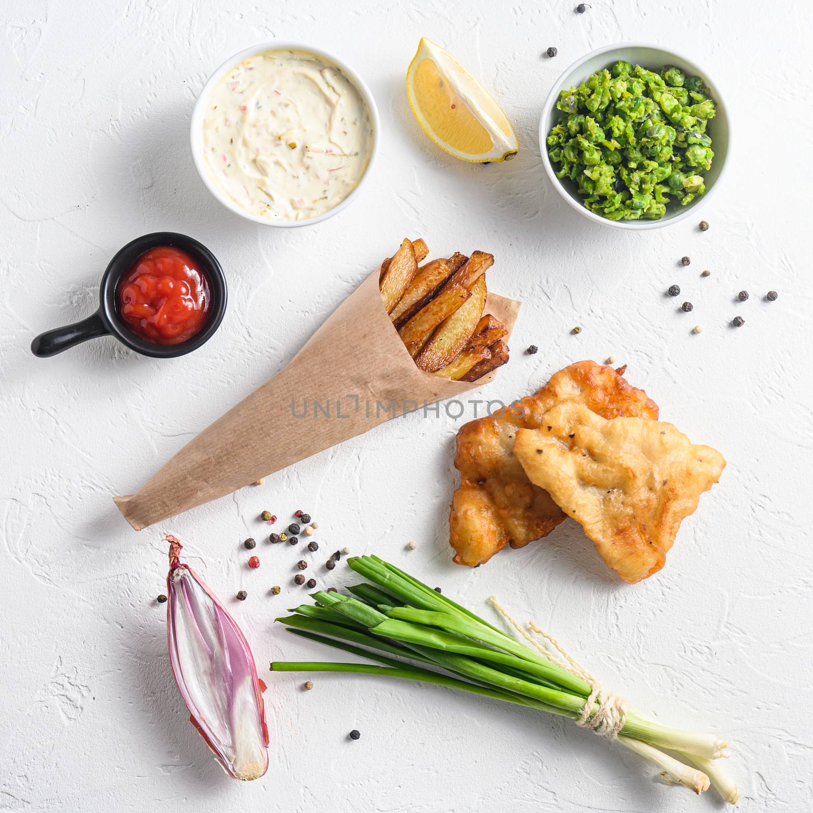 Fried fish and chips in a paper cone on white background with all components classic recipe takeaway food top view white stone textured background square crop by Ilianesolenyi