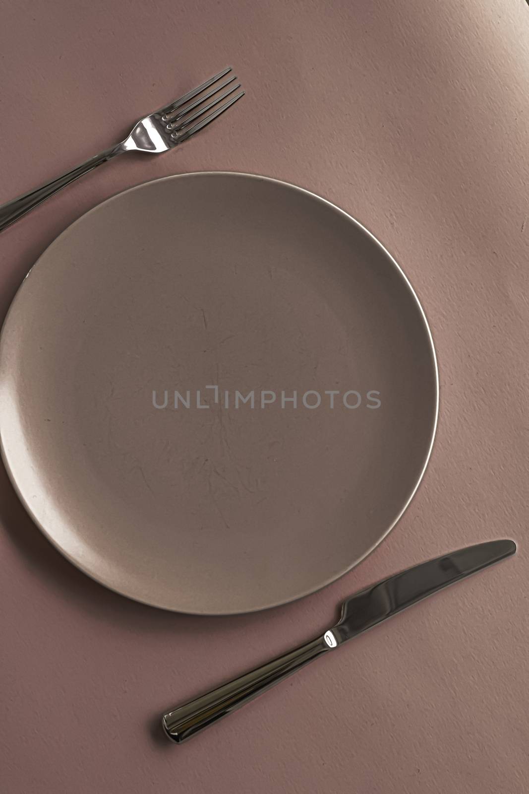 Empty plate and cutlery as mockup set on brown background, top tableware for chef table decor and menu branding by Anneleven