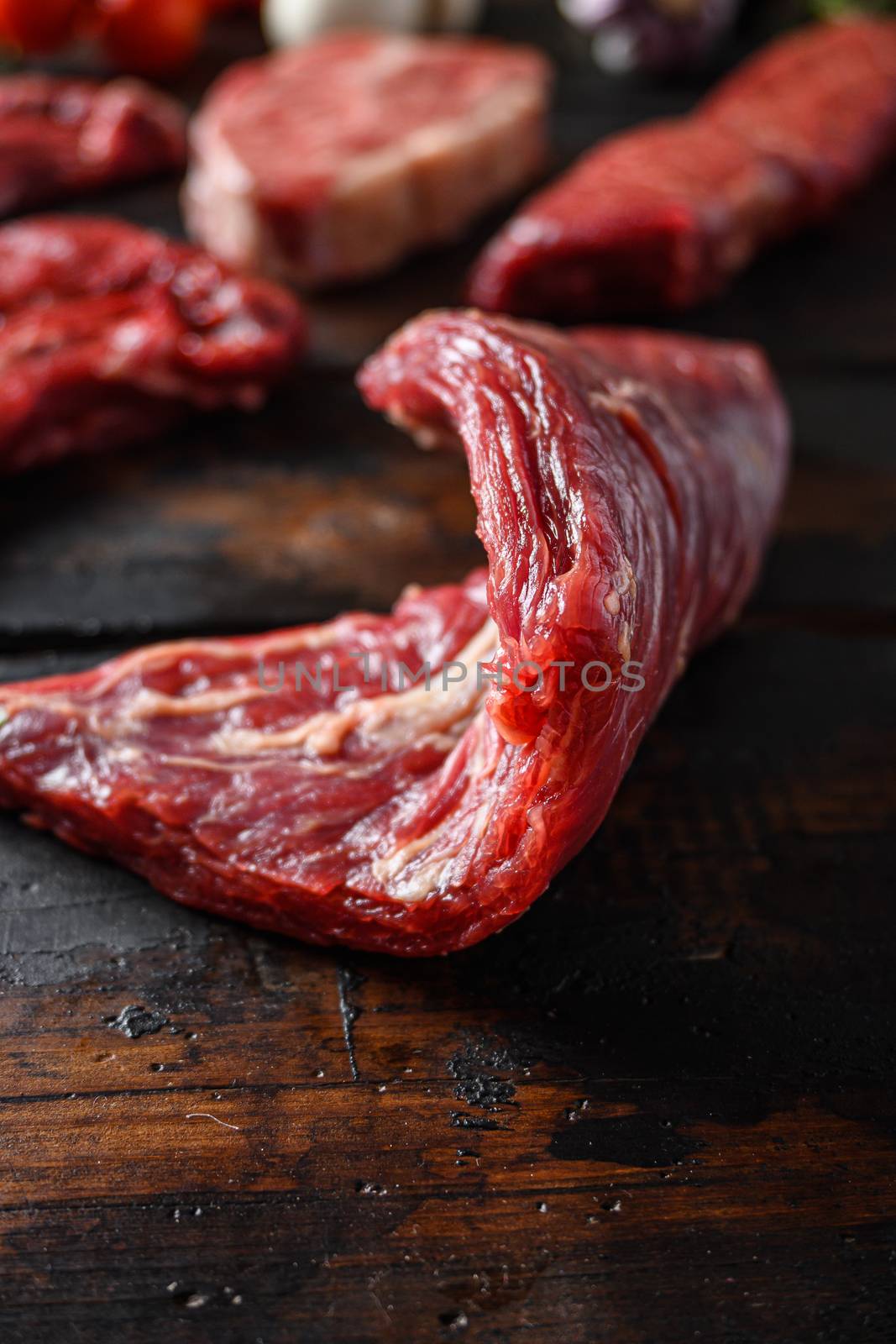 Bio Flank bavette or flap steak beef t steak near tri-tip and top blade oyster cuts close up in front of other cuts in butchery on old wood table side view selective focus by Ilianesolenyi