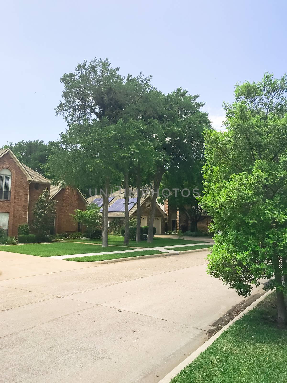 Typical upscale suburban residential neighborhood near Dallas, Texas, America with solar panel roof house and mature trees.