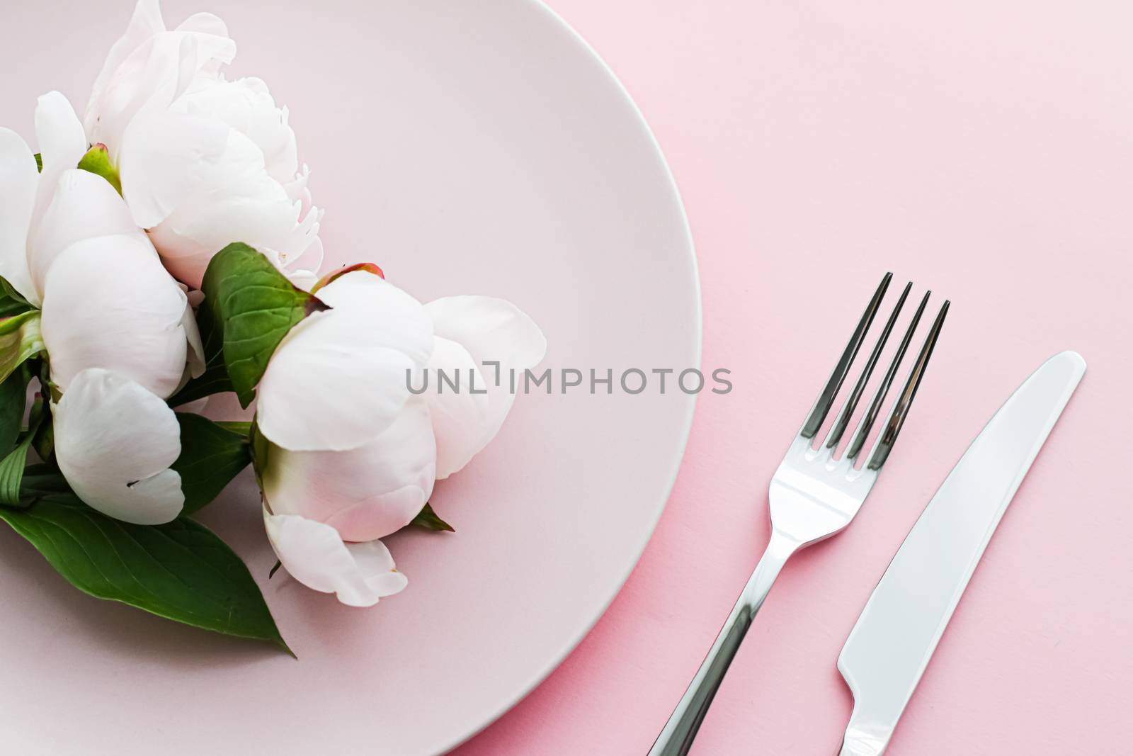 Dining plate and cutlery with peony flowers as wedding decor set on pink background, top tableware for event decoration and menu branding by Anneleven