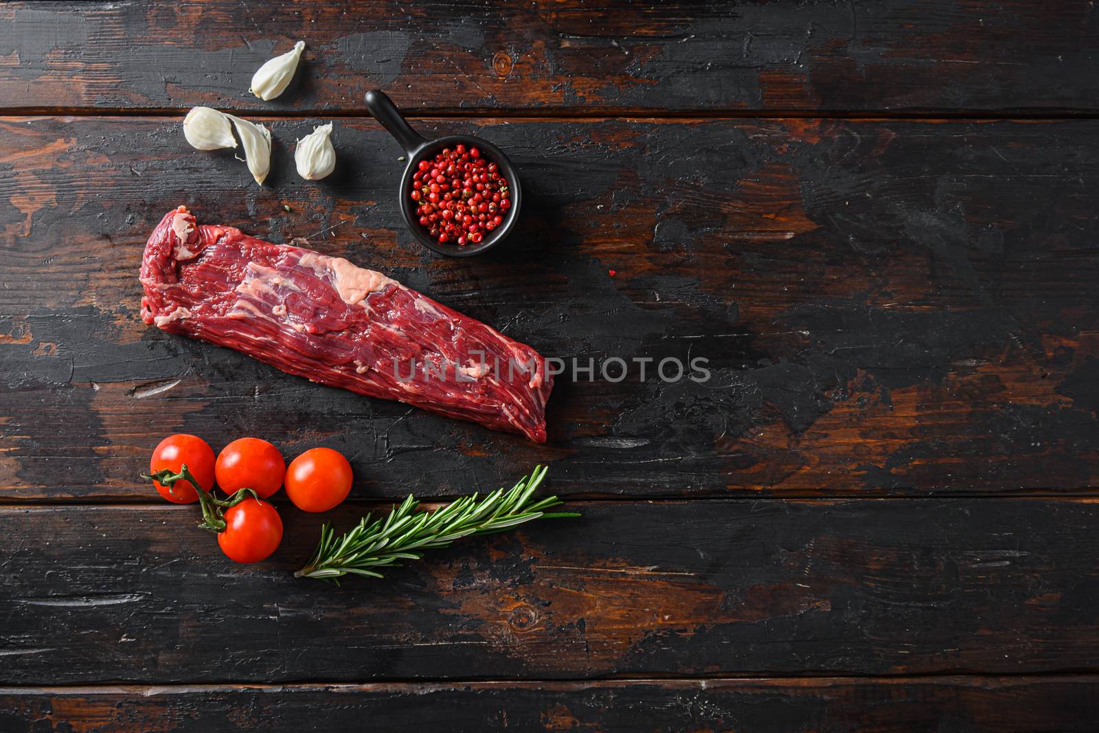 Organic machete steak or hanging tende cut, with rosemary over wood background Top view space for text by Ilianesolenyi