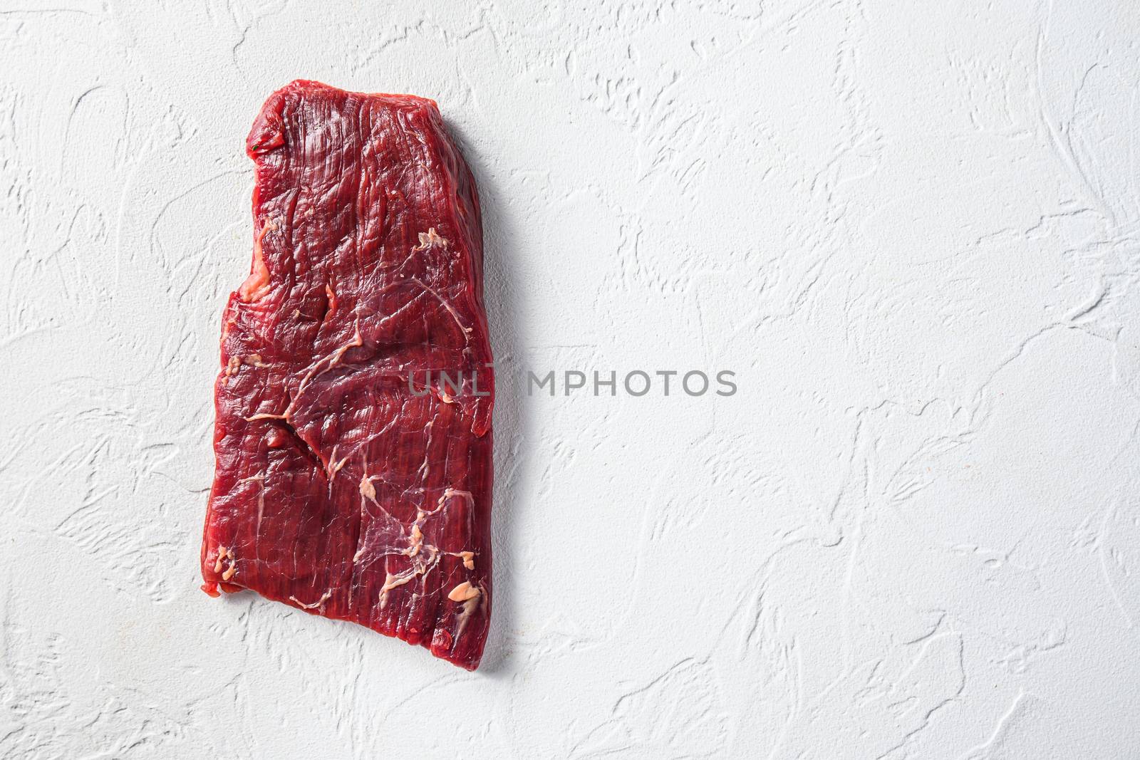 Raw skirt or flank steak,on a white stone background top view space for text. by Ilianesolenyi