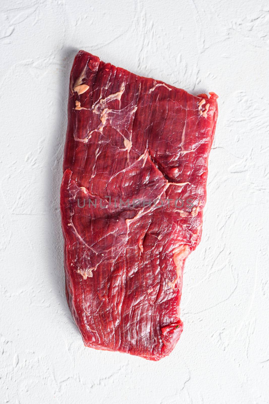 Raw skirt or flank steak,on a white stone background top view vertical by Ilianesolenyi