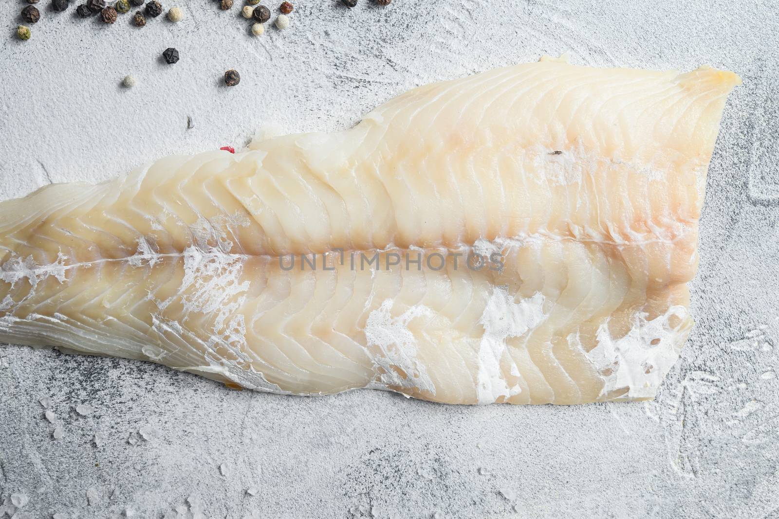 Cod fillets on a grey concrete background for the preparation of a healthy dish top view close up.