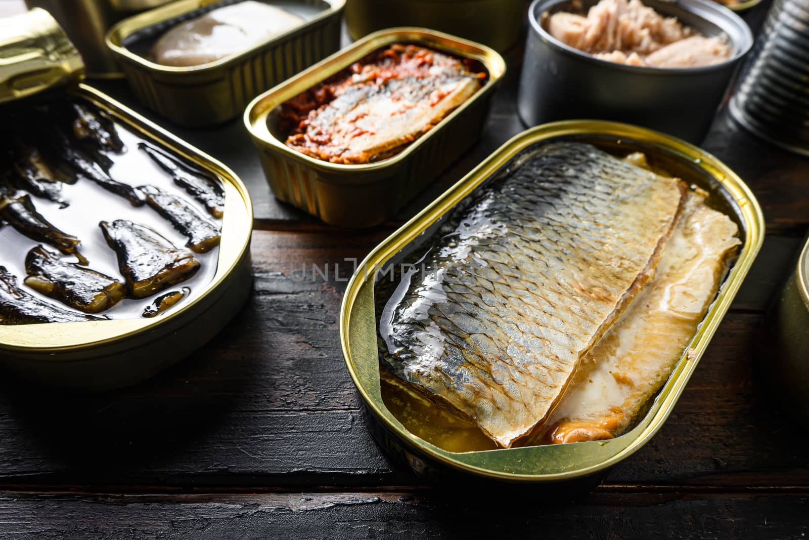 Cans of herring and different types of fish and seafood, over rustic wooden dark planks side view. New wide angle. by Ilianesolenyi