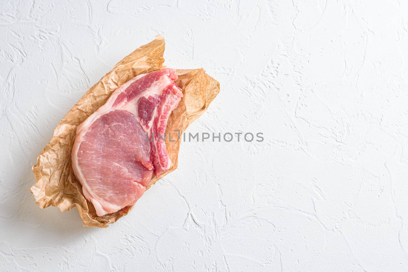 Raw organic pork chop steak top wiev on white textured background top view with space for your text by Ilianesolenyi
