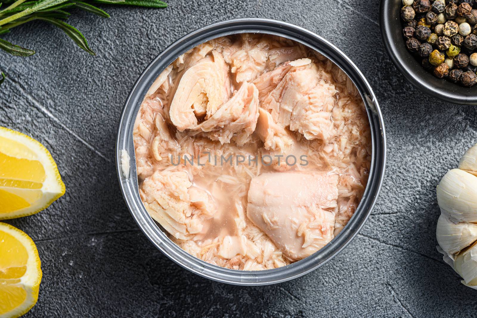 canned tuna open can with fresh herbs garlic and lemon ingredients for preservs top view close up.