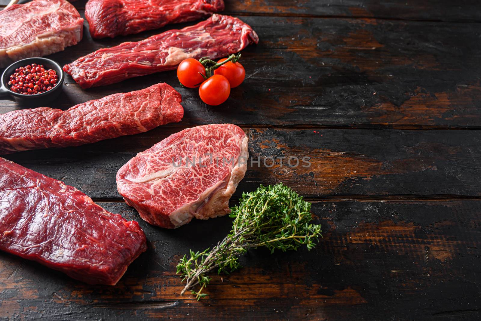 Set of fresh raw alternative beef steaks flap flank Steak, machete steak or skirt cut, Top blade or flat iron beef and tri tip, triangle roast with denver cut side view over old butcher wood table close up space for text by Ilianesolenyi