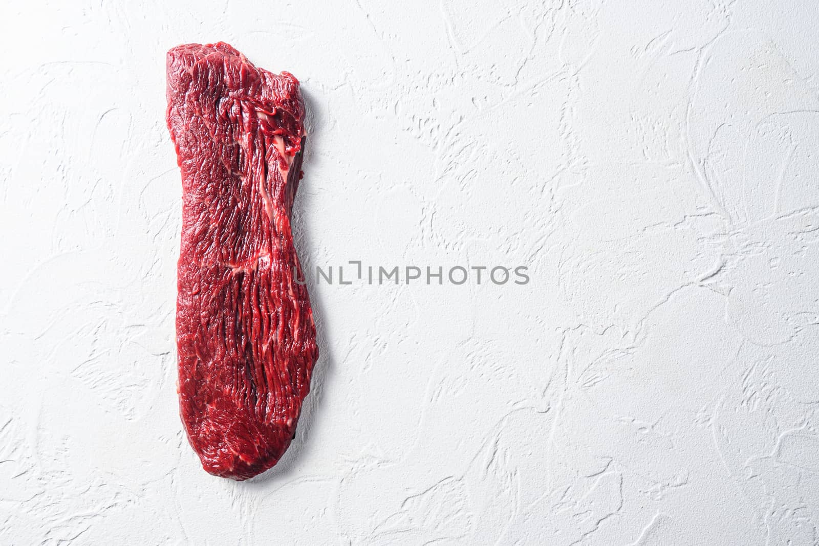 Raw tri tip, bottom sirloin steak on a white stone background top view space for text