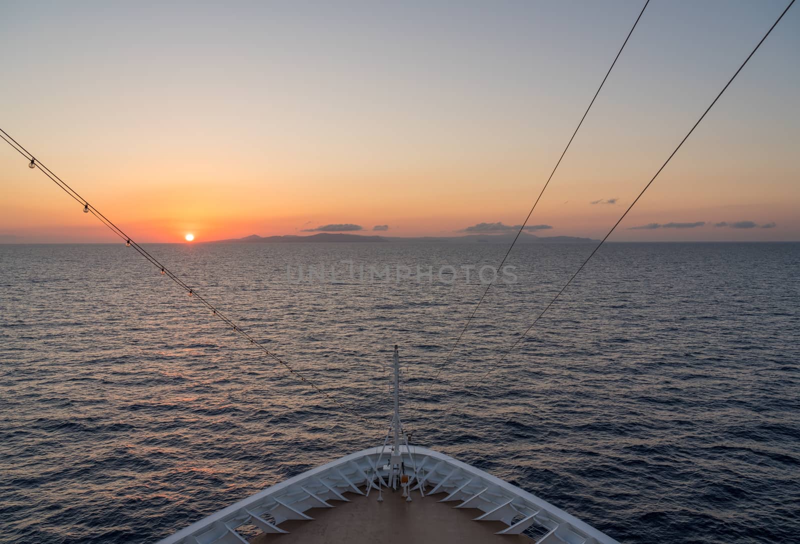 Small cruise liner sailing across the ocean as dawn starts to light the sky