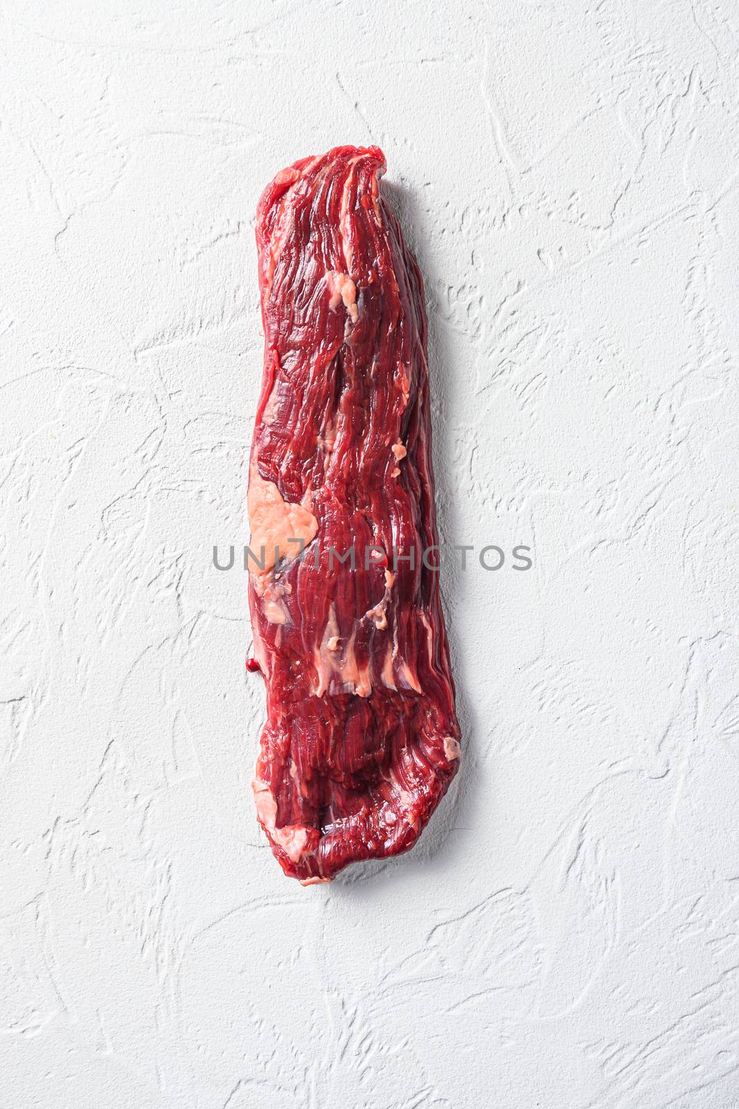 Raw skirt, machete steak on a white stone background vertical.