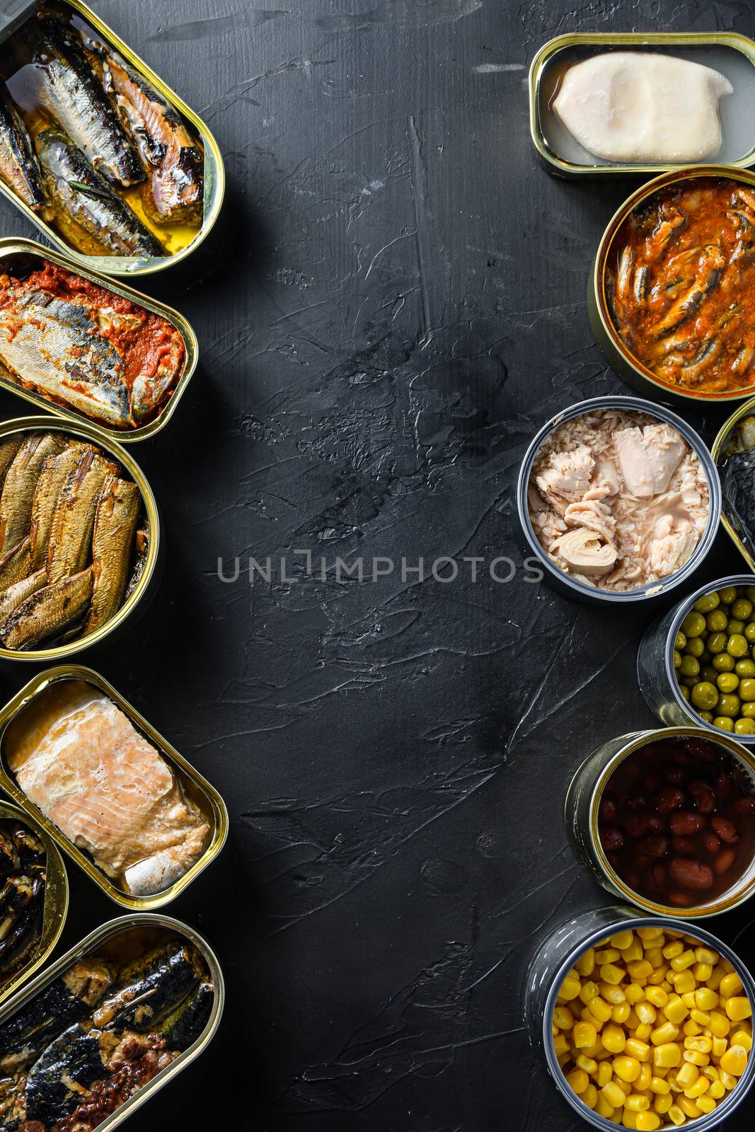 Canned conserve products in tin cans. with fresh organic ingridients Saury, mackerel, sprats, sardines, pilchard, squid, tuna pinapple, corn, peas, mango , beans, over black stone textured background top view copyspace side by side vertical center text concept.