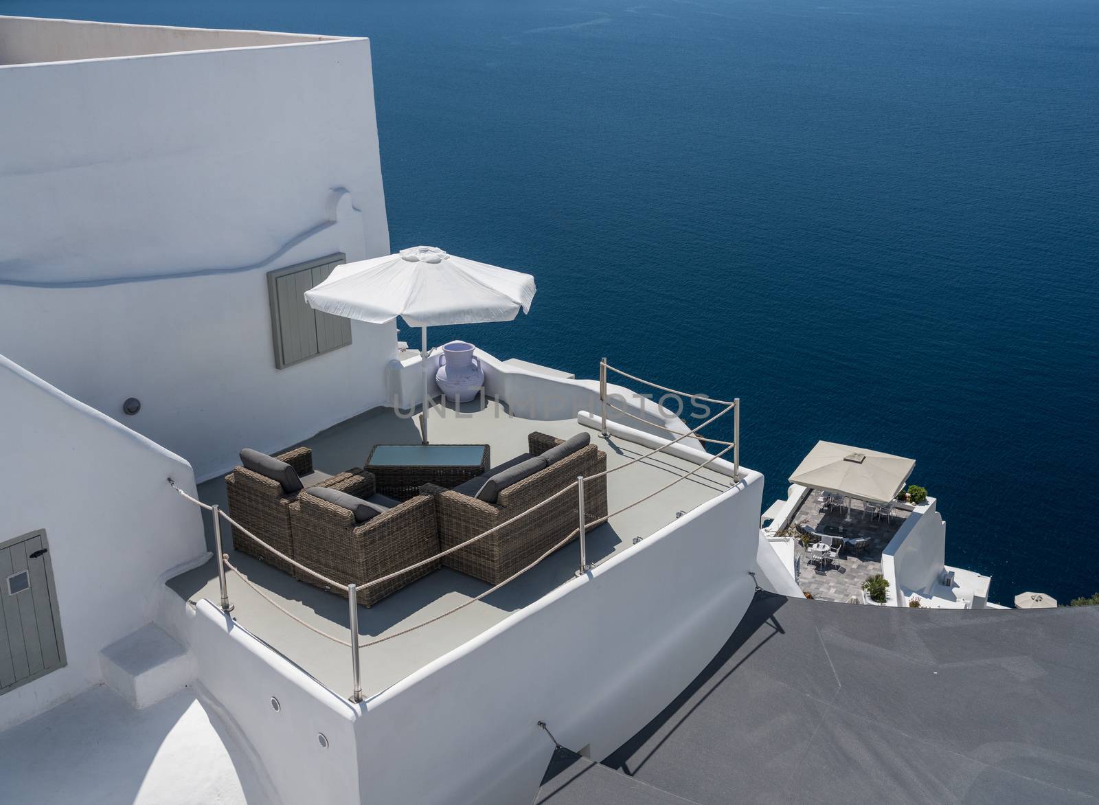 Patio furniture on deck above blue ocean in Santorini