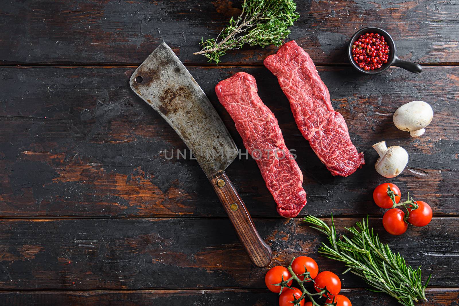 Raw denver machete steak on a meat cleaver. Black background. Top view copyspace.