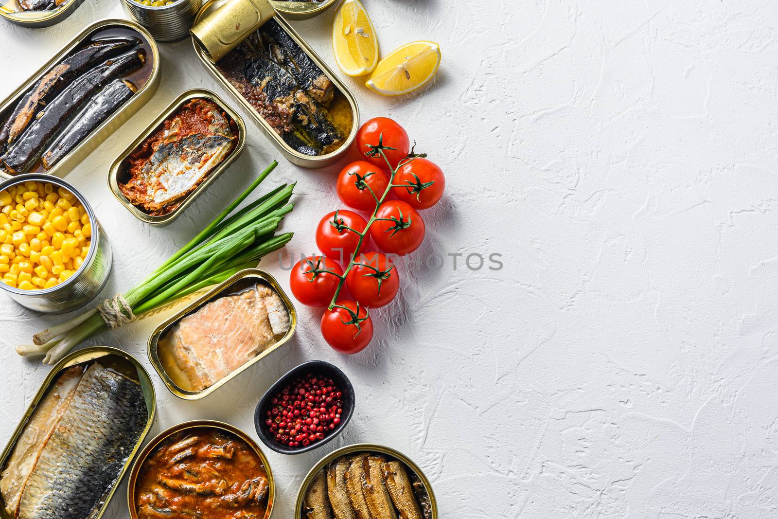Assortment of canned preserves food in tin open cans. with fresh organic ingridients Saury, mackerel, sprats, sardines, pilchard, squid, tuna pinapple, corn, peas, mango , beans, over white textured background top view space for text.