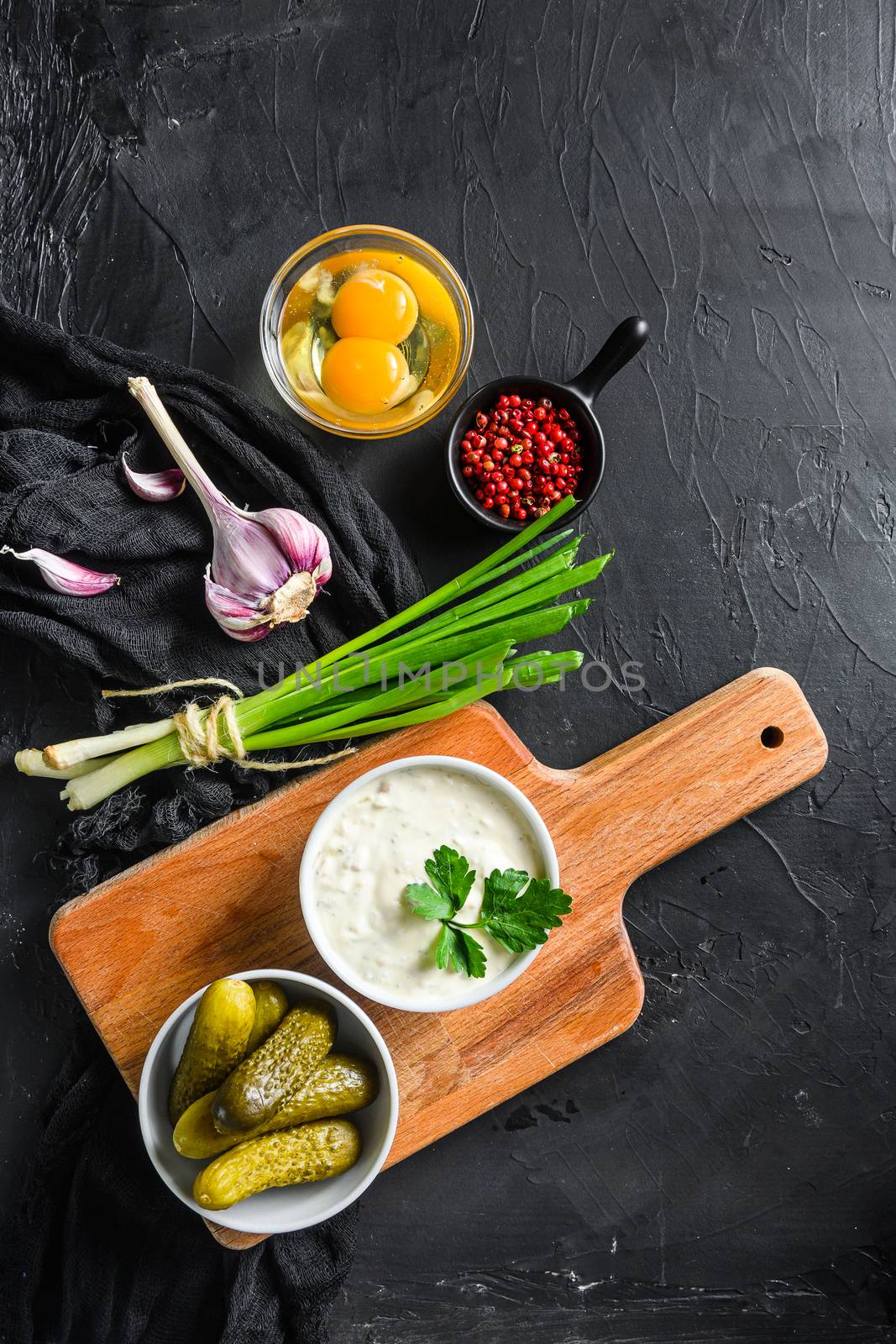 Tartar Sauce with organic ingredients pickles, capers, dill, parsley, garlic, lemon and mustard rose peppercorns on a dark black stone concrete background. Horizontal, top view vertical by Ilianesolenyi