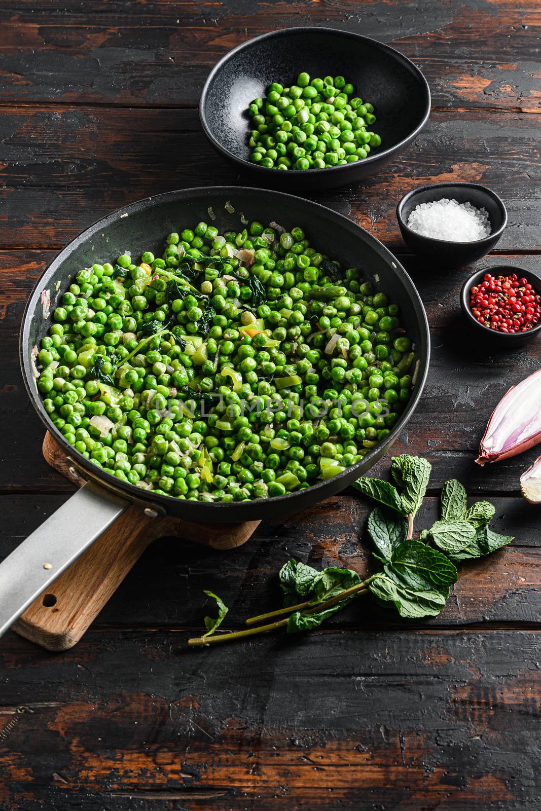 keto mushy peas ingredients in frying pan and peas in bowl with mint shallot pepper and salt top view over old pub wood table vertical.