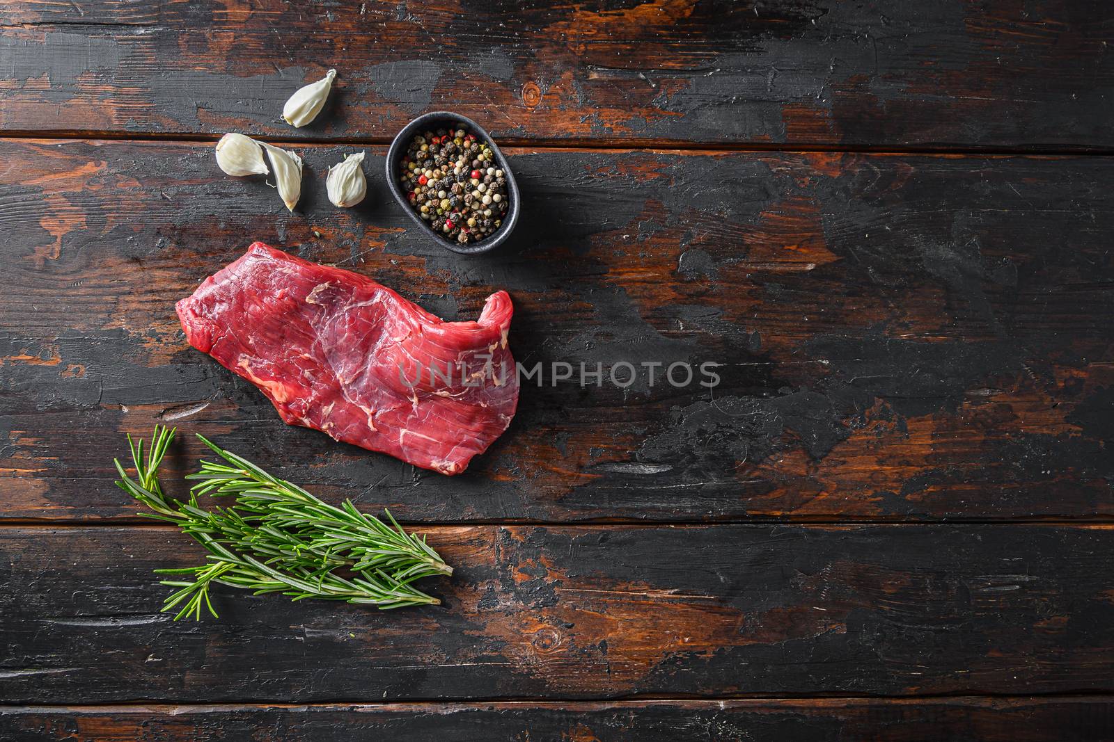 Flank, Bavette steak with seasonings, and fresh herbs raw meat, marbled beef . Dark wood rustic background. Top view space for text.