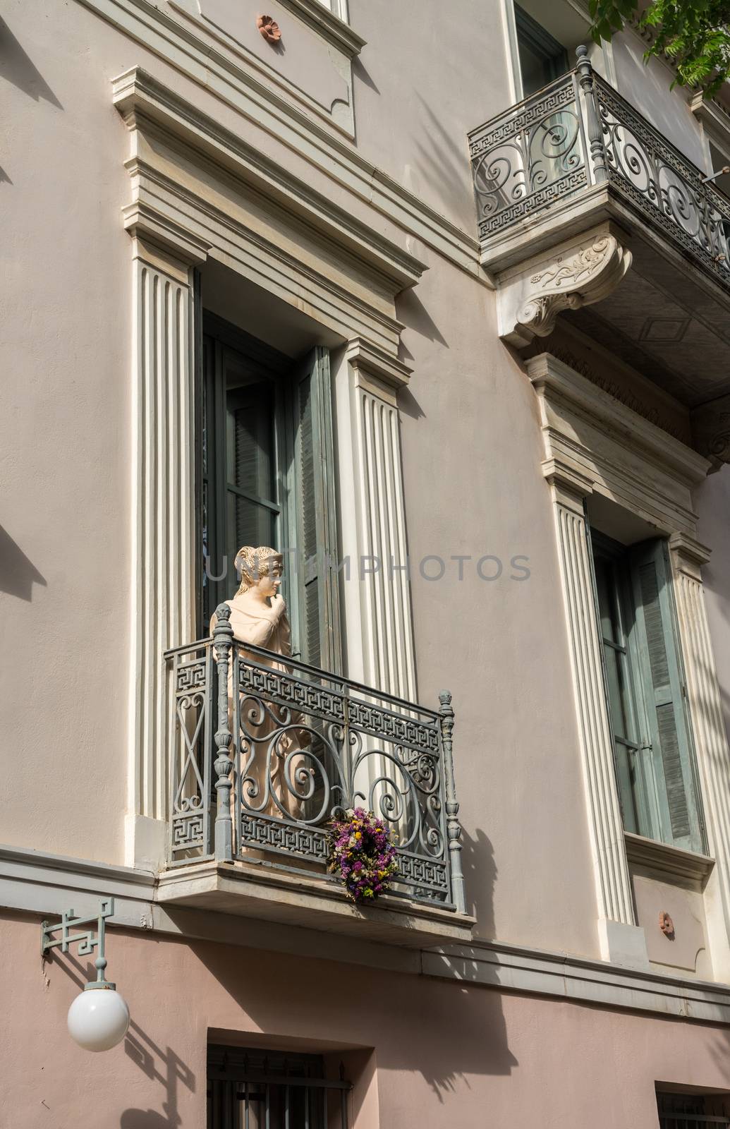 Statue on a wrought iron balcony in ancient district or neighborhood of Plaka in Athens by the Acropolis