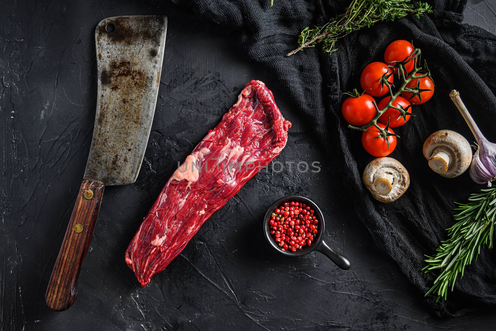 Organic machete or skirt steak near butcher knife with pink pepper and rosemary. Black background. Top view. by Ilianesolenyi