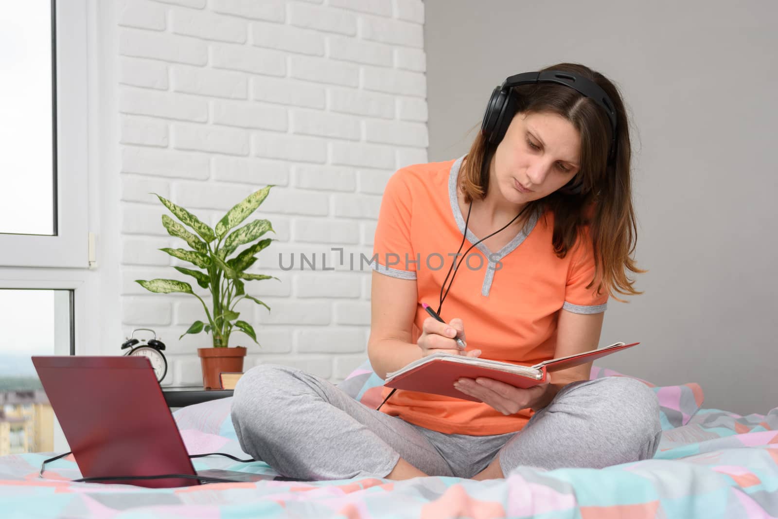 Girl student at home writes online lecture materials in a notebook