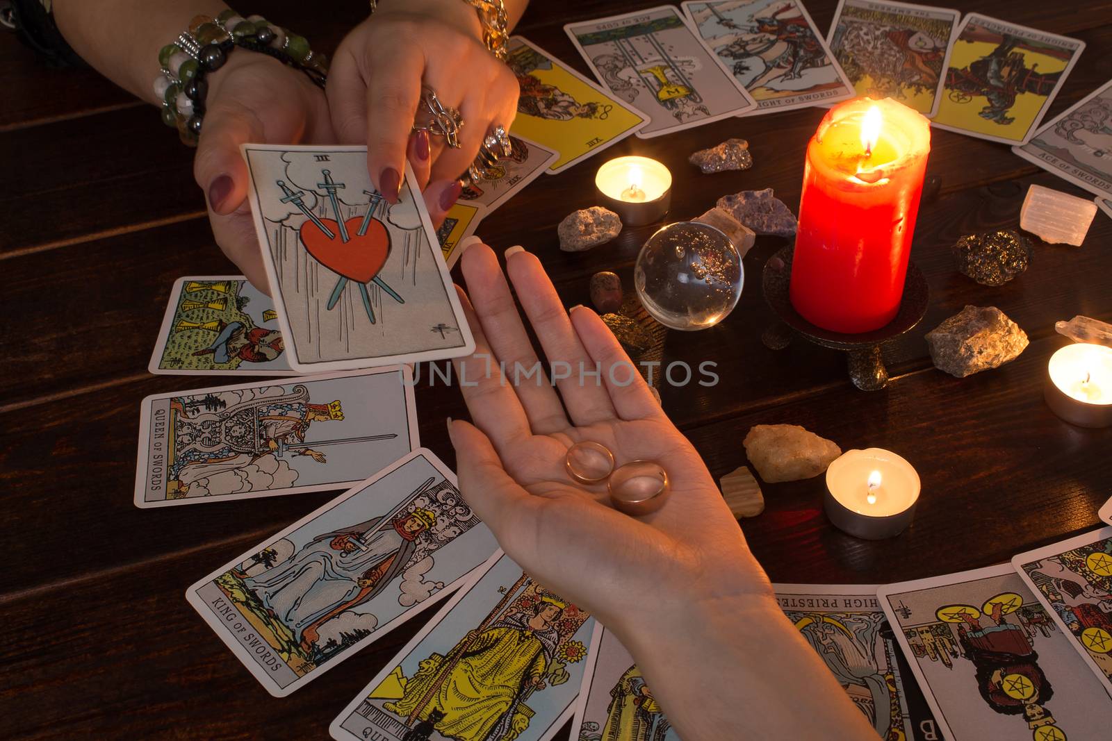 Bangkok,Thailand,March.15.20.The girl holds wedding rings on her hand with Tarot cards,crystals,a magic ball and a lighted candle.Fortune telling  for love, the rite of love spell