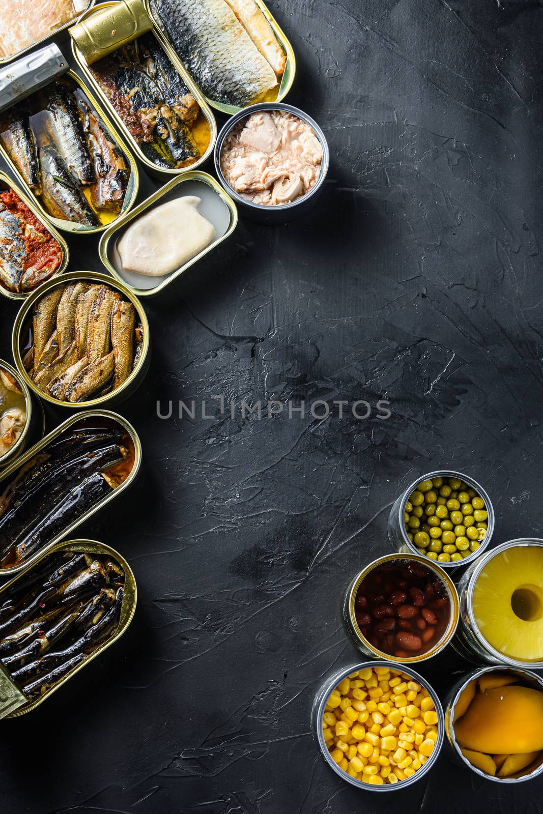 Canned conserve products in tin cans. with fresh organic ingridients Saury, mackerel, sprats, sardines, pilchard, squid, tuna pinapple, corn, peas, mango , beans, over black stone textured background top view space for text vertical corner concept by Ilianesolenyi