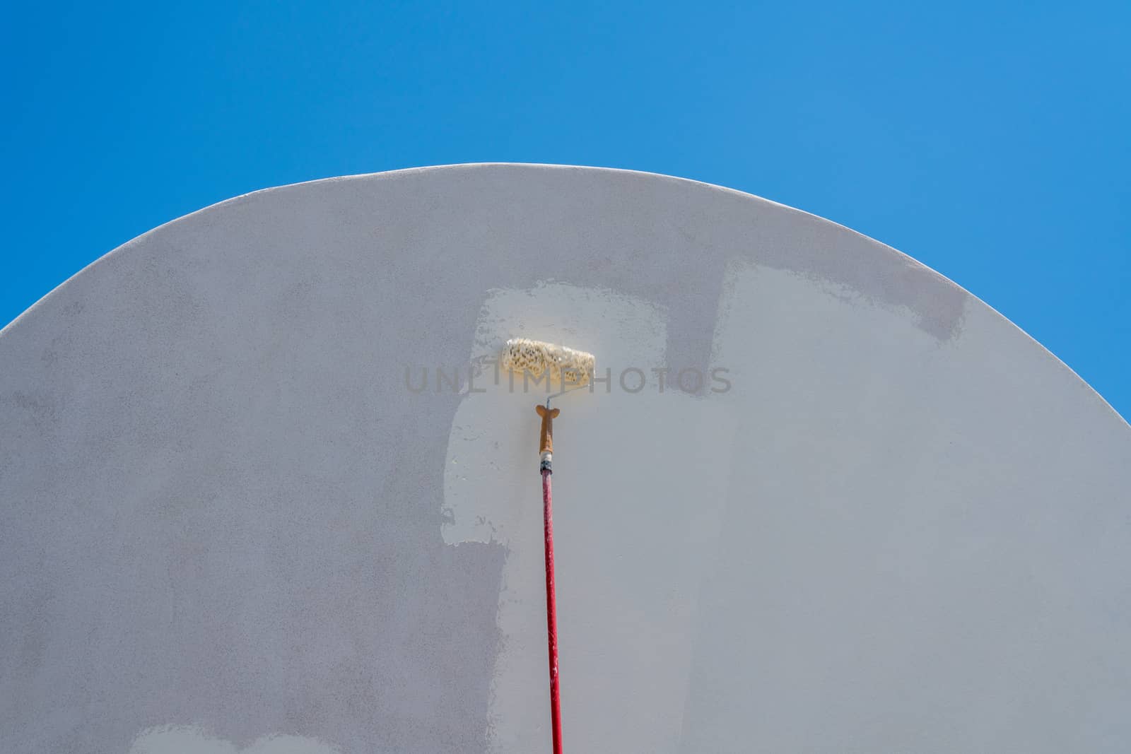 White paint being applied by roller to traditional house in Santorini