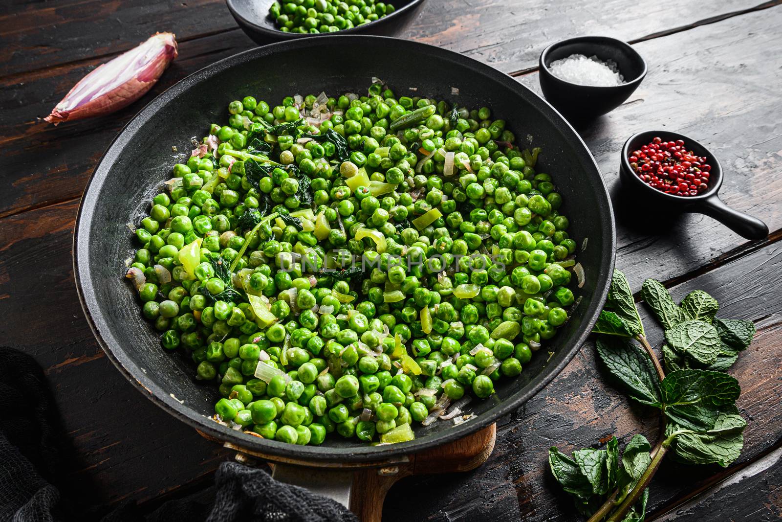 Mushy peas gluten free recipe in frying pan and peas in bowl with mint shallot pepper and salt over old pub wood surface close up new wide angel view by Ilianesolenyi