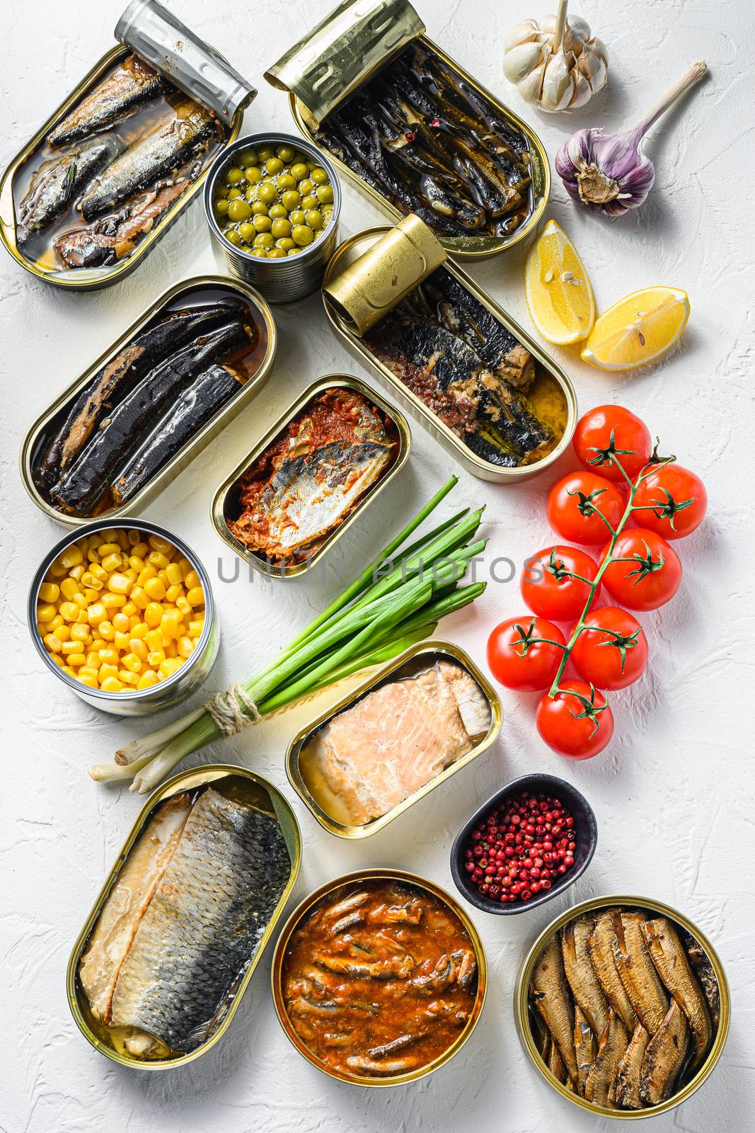 Assortment of canned preserves food in tin open cans. with fresh organic ingridients Saury, mackerel, sprats, sardines, pilchard, squid, tuna pinapple, corn, peas, mango , beans, over white textured background top view vertical by Ilianesolenyi