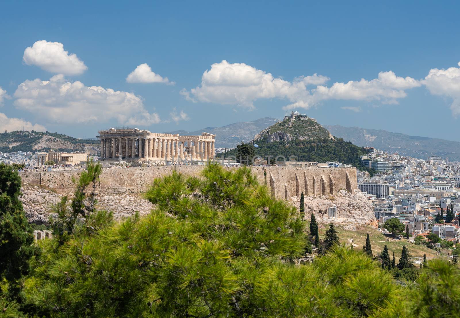 Acropolis and Lycabettus Hill framed by trees from the summit of Lycabettus hill