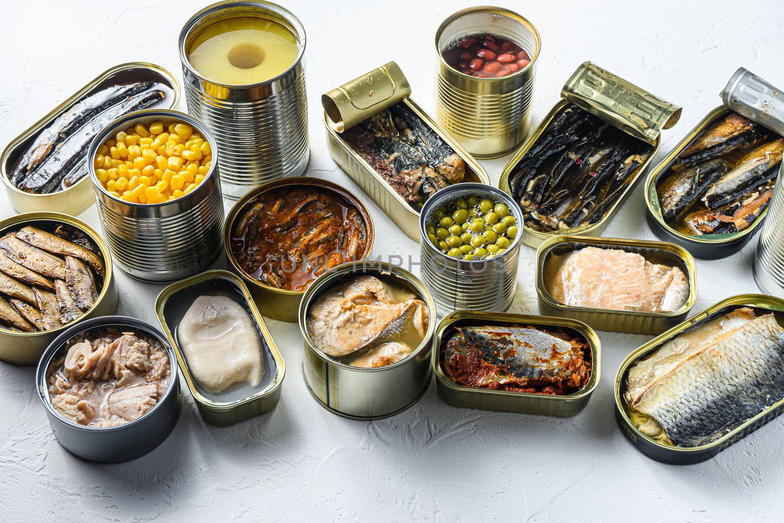 Assortment of canned preserves food in cans, conserve Saury, mackerel, sprats, sardines, pilchard, squid, tuna pinapple, corn, peas, mango , beans, over white textured background side view. by Ilianesolenyi