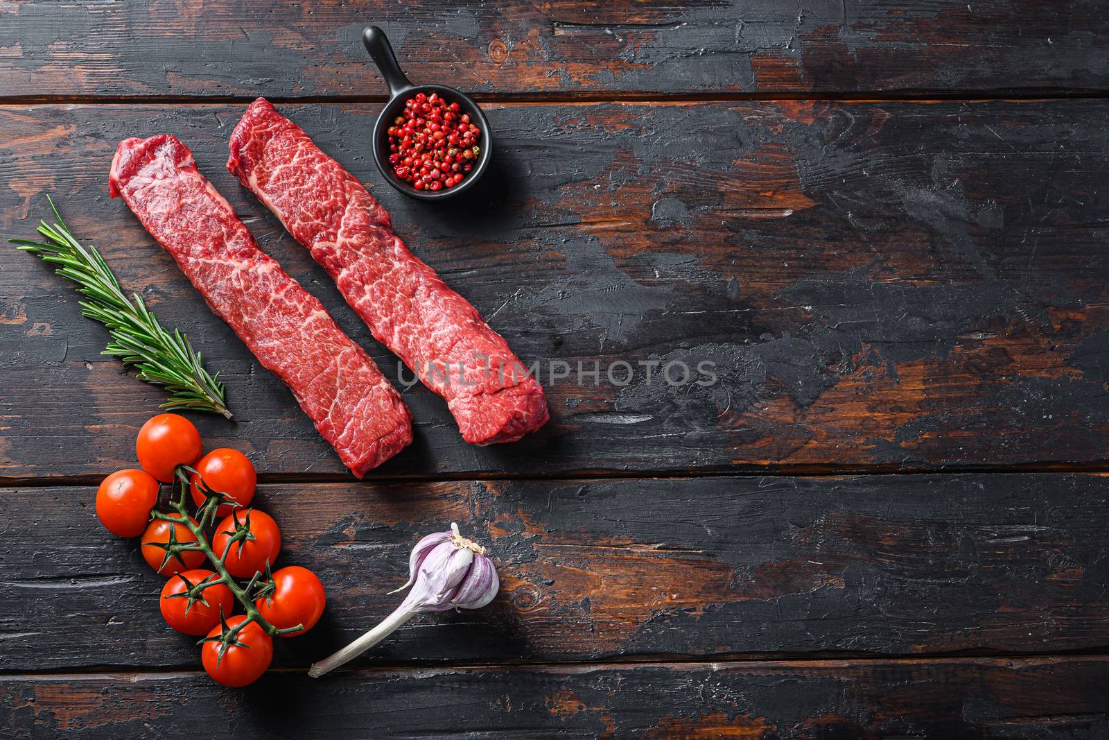 Raw denver steak or organic top blade wuth herbs top view on old wooden planks surface space for text.