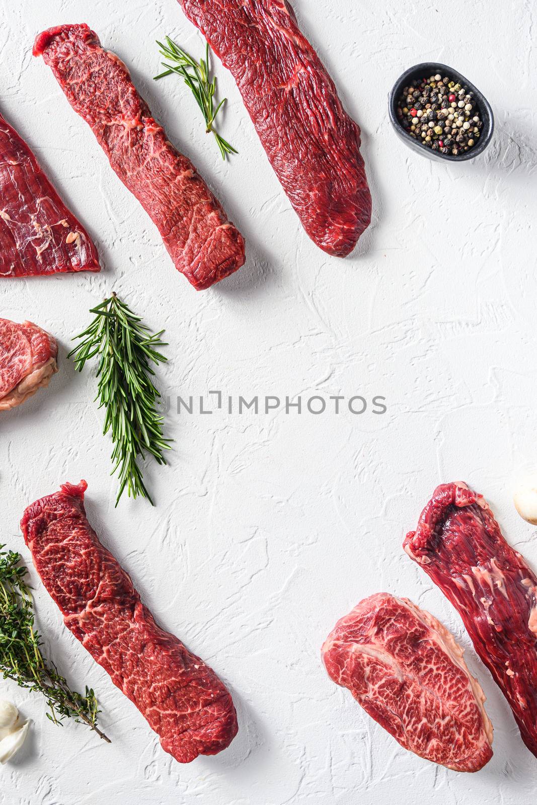 Set of different alternative types of raw beef steaks,on a white stone background top view concept frame in corners space for text vertical in center by Ilianesolenyi