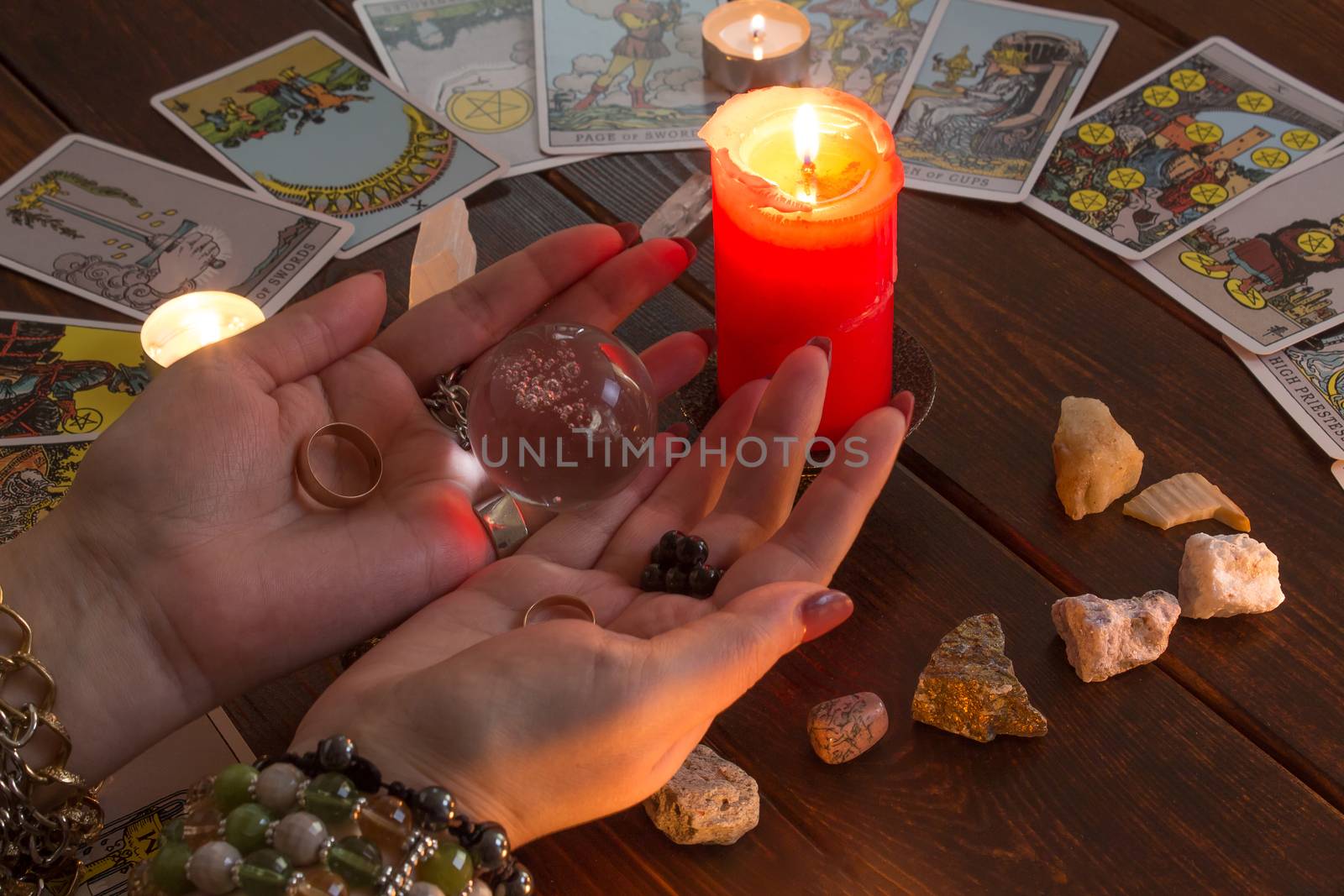 Bangkok,Thailand,March.15.20.The girl holds wedding rings on her hand with Tarot cards with heart,crystals,a magic ball and a lighted candle.Fortune telling for love, the rite of love spell.