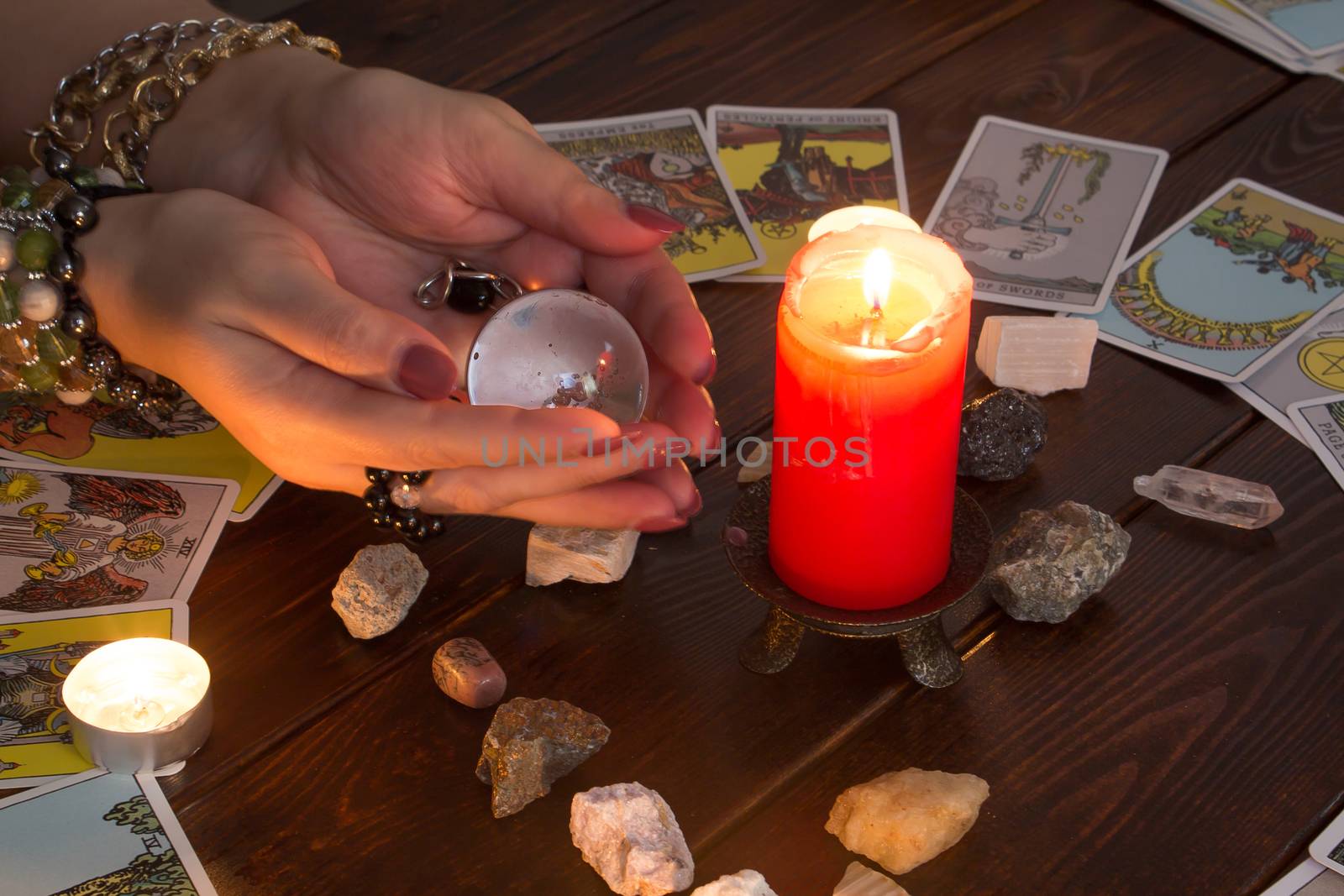 Bangkok,Thailand,March.15.20. A fortune teller holds a magic ball.On the table are fortune-telling cards and lighted candle.Magic sessions with clairvoyance cards.Reading maps by candlelight