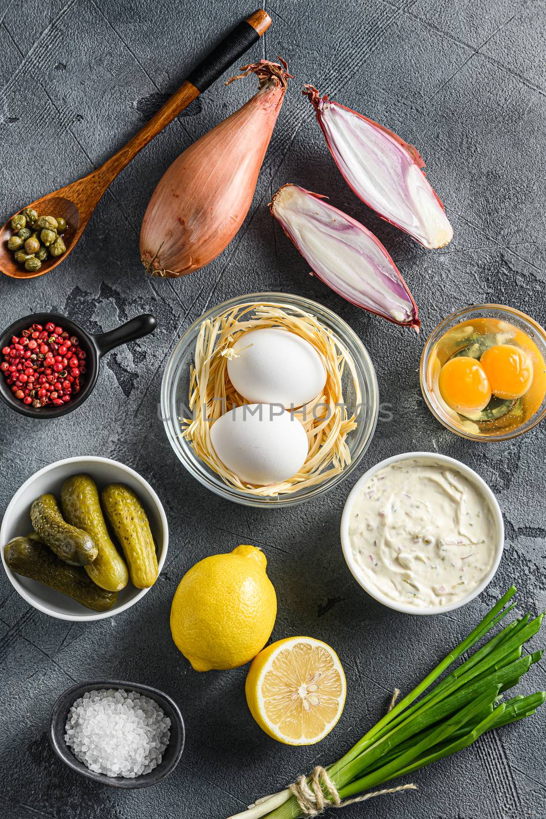 Tartar sauce in a bowl with organic ingredients from classic recipe top view on rustic grey concrete table surface top view.