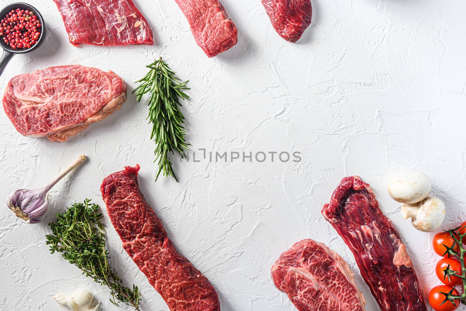 Set of different alternative types of raw beef steaks,on a white stone background top view concept frame in corners space for text in center by Ilianesolenyi