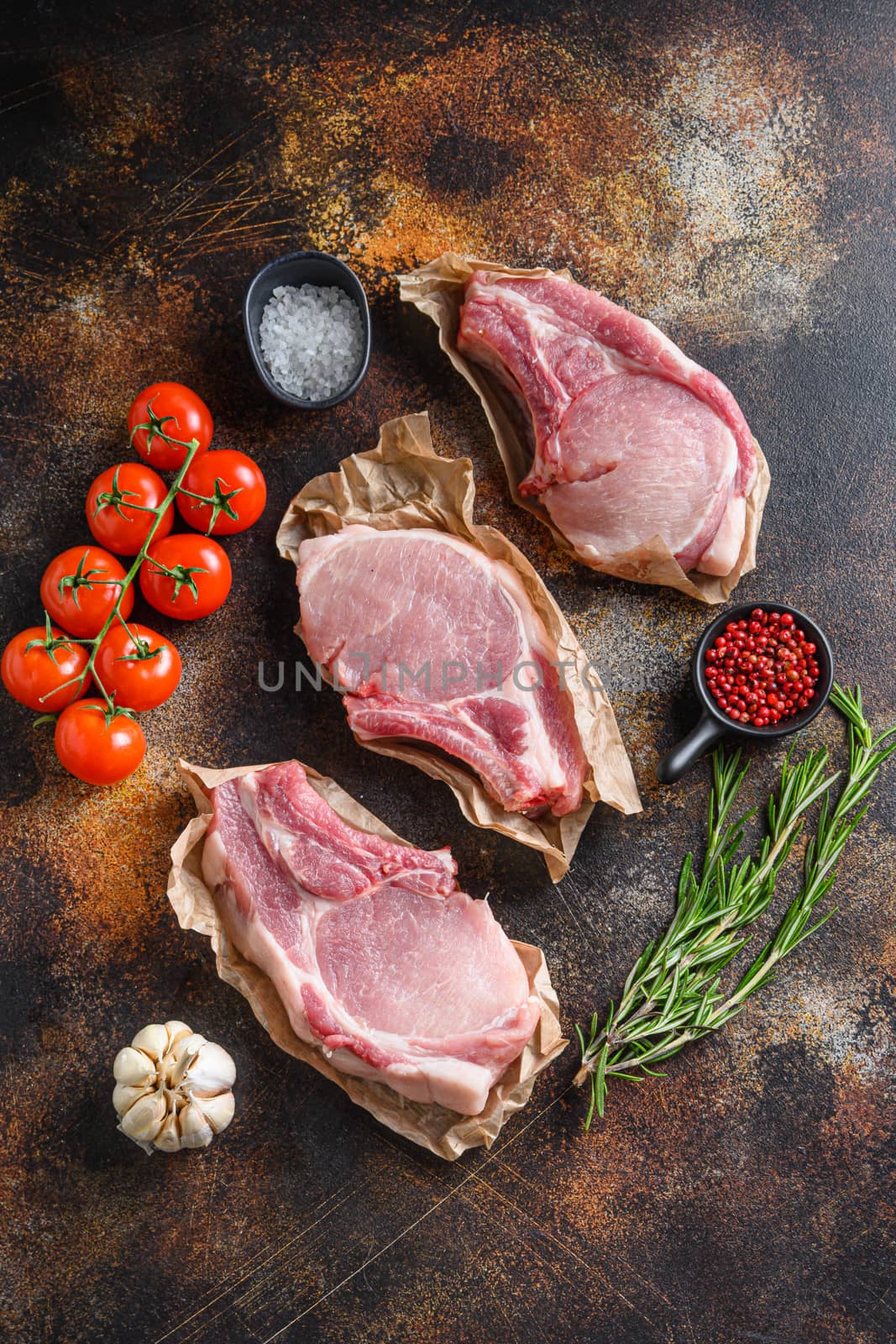 Raw pork meat from above on craft paper with ingredients for grill rosematy over rustic old metal background stock photo by Ilianesolenyi