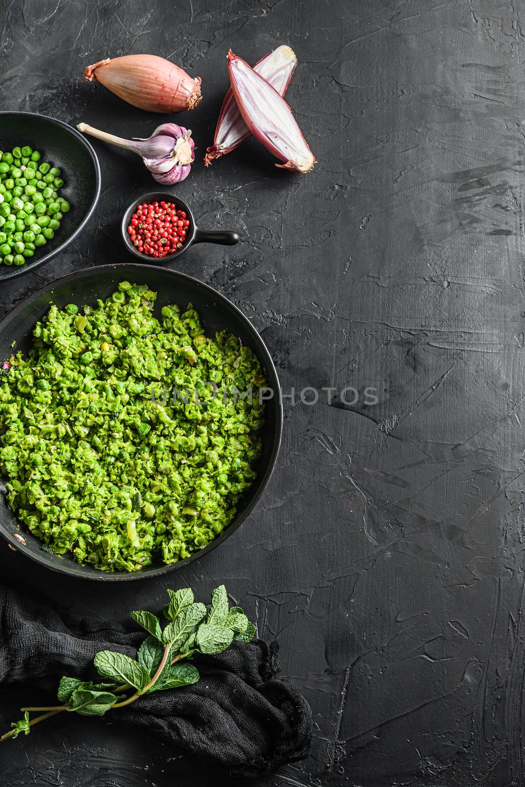 mushy peas gluten free cooked frying pan and peas in bowl with mint shallot pepper and salt s black stone surface organic keto food top view space for text vertical concept.