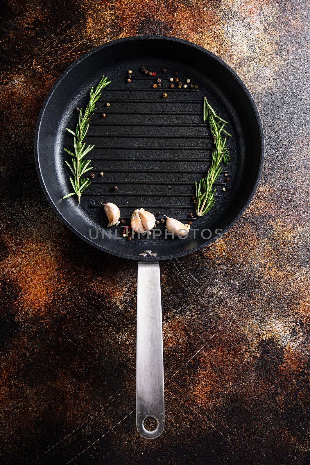 barbecue grill frying pan or skillet on rustic metall surface with herbs for cooking top view concept for text or objects by Ilianesolenyi