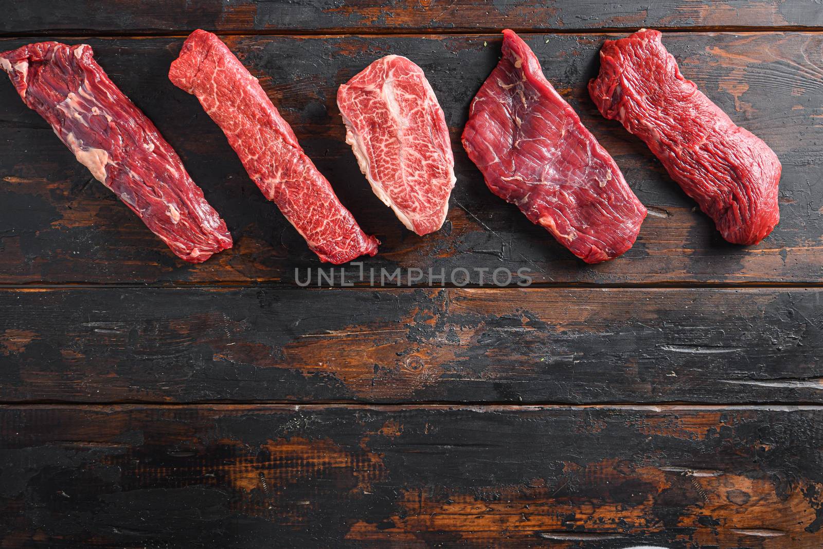 A set of different types of raw beef steaks alternative cut flap flank Steak, machete steak or skirt cut, Top blade or flat iron beef and tri tip, triangle roast with denver cut top view space for text.